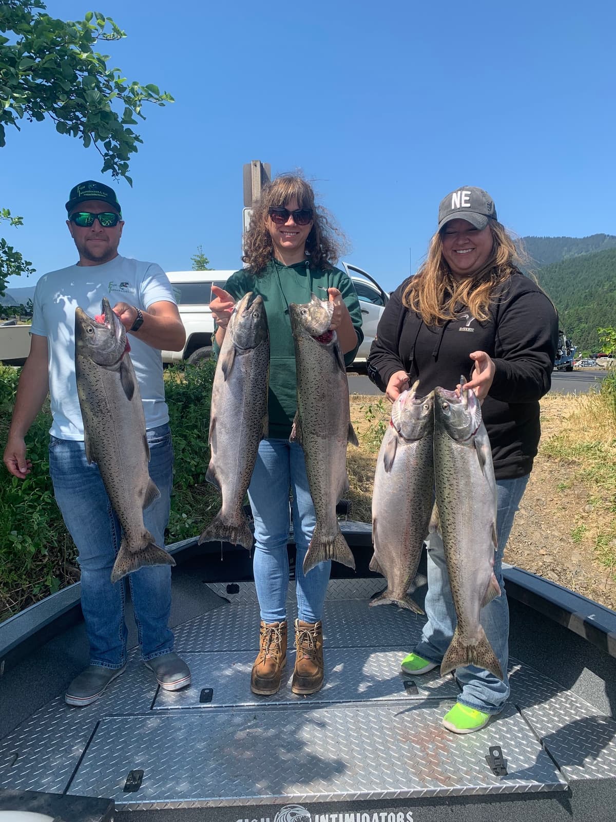 Three anglers holding large chinook salmon on Columbia River boat