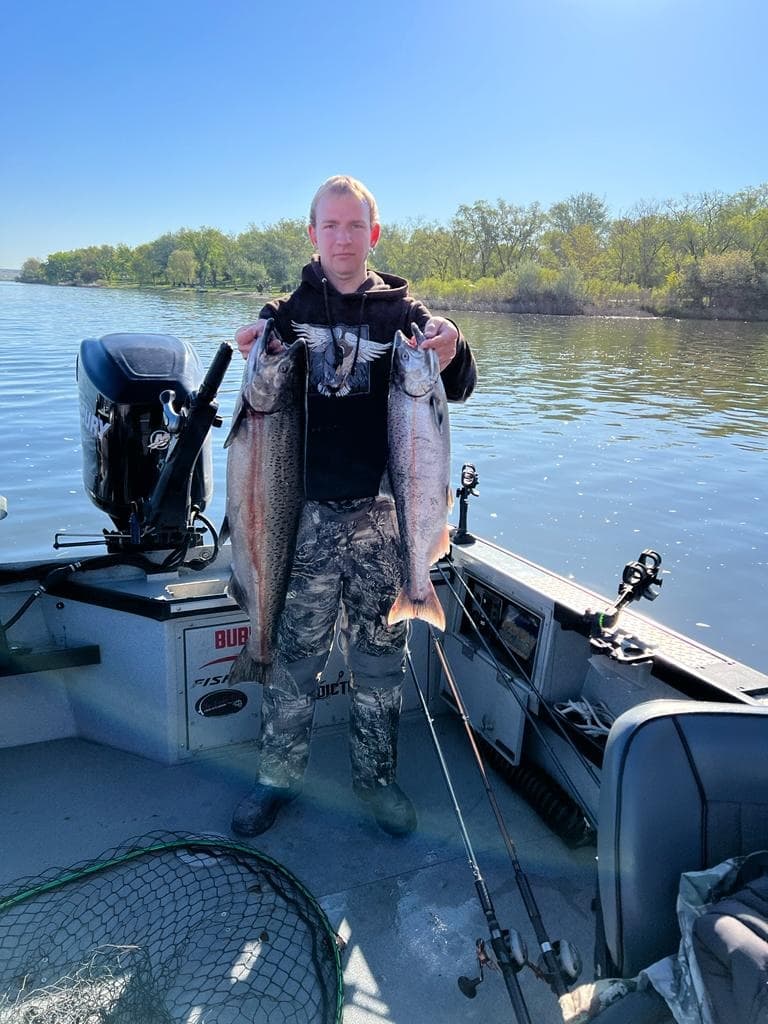 Angler holding two large chinook salmon on guided fishing boat