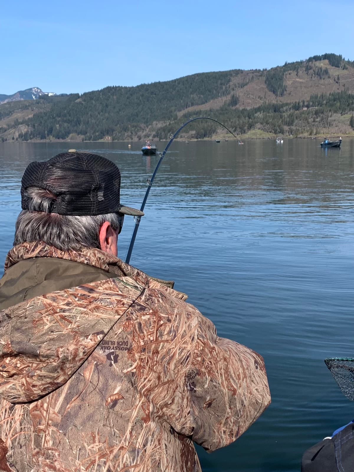 Angler fighting a fish with rod bent on the Columbia River gorge