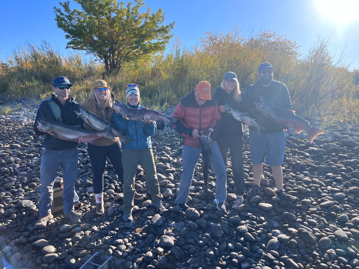 Group of five displaying large salmon on rocky Columbia River bank in Washington