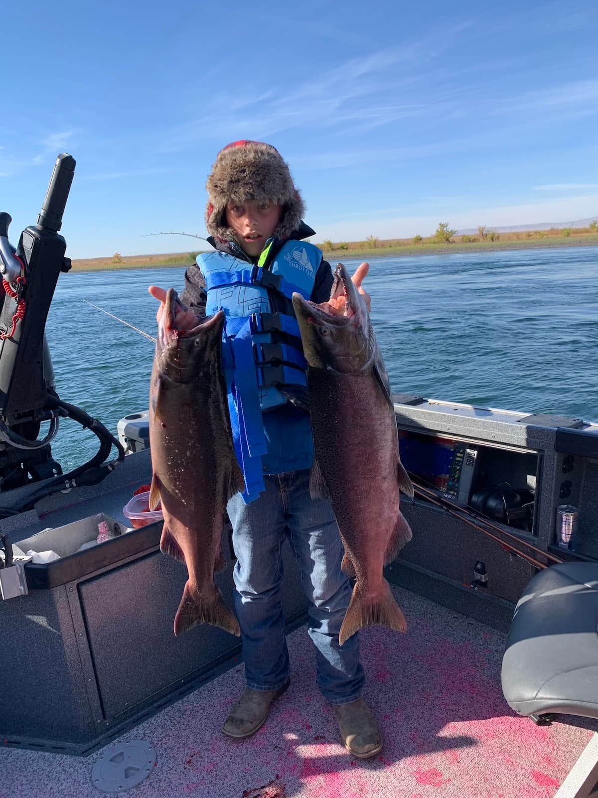Child holding two large salmon on guided Columbia River fishing boat in Washington