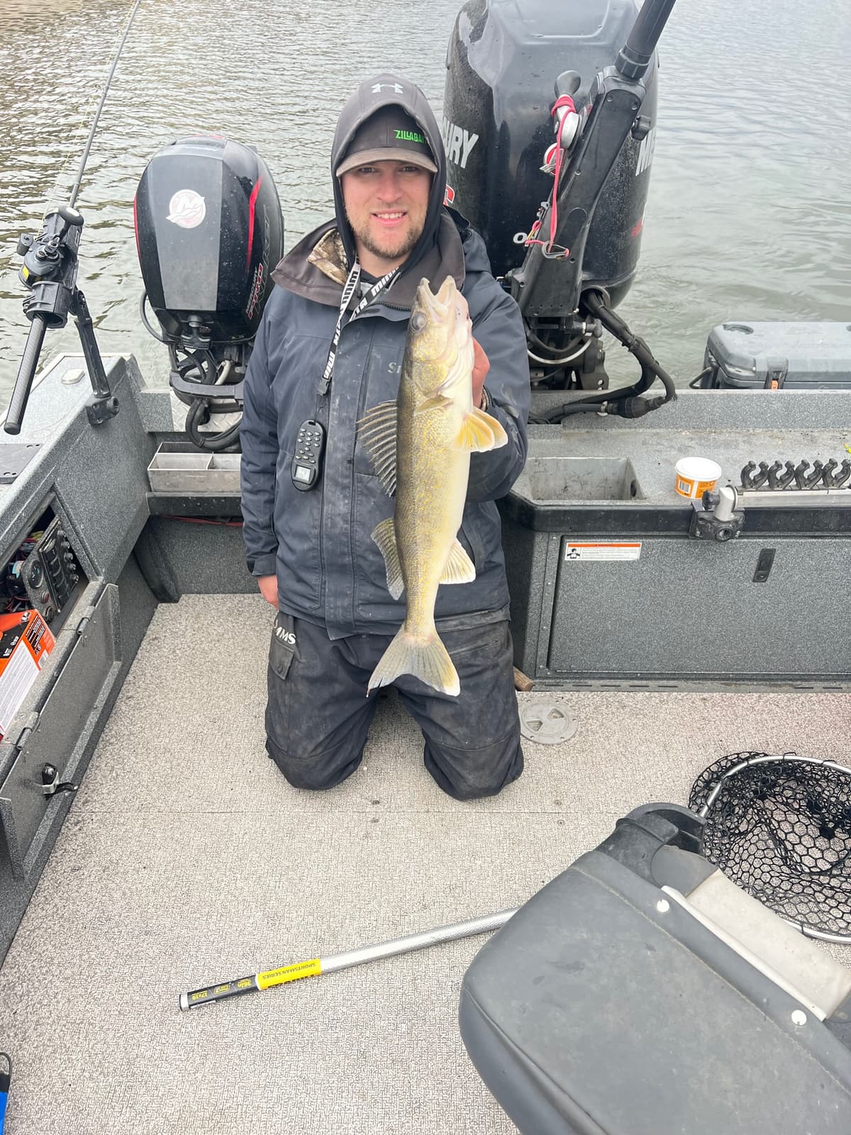 Man kneeling on boat holding walleye on Columbia River guided trip