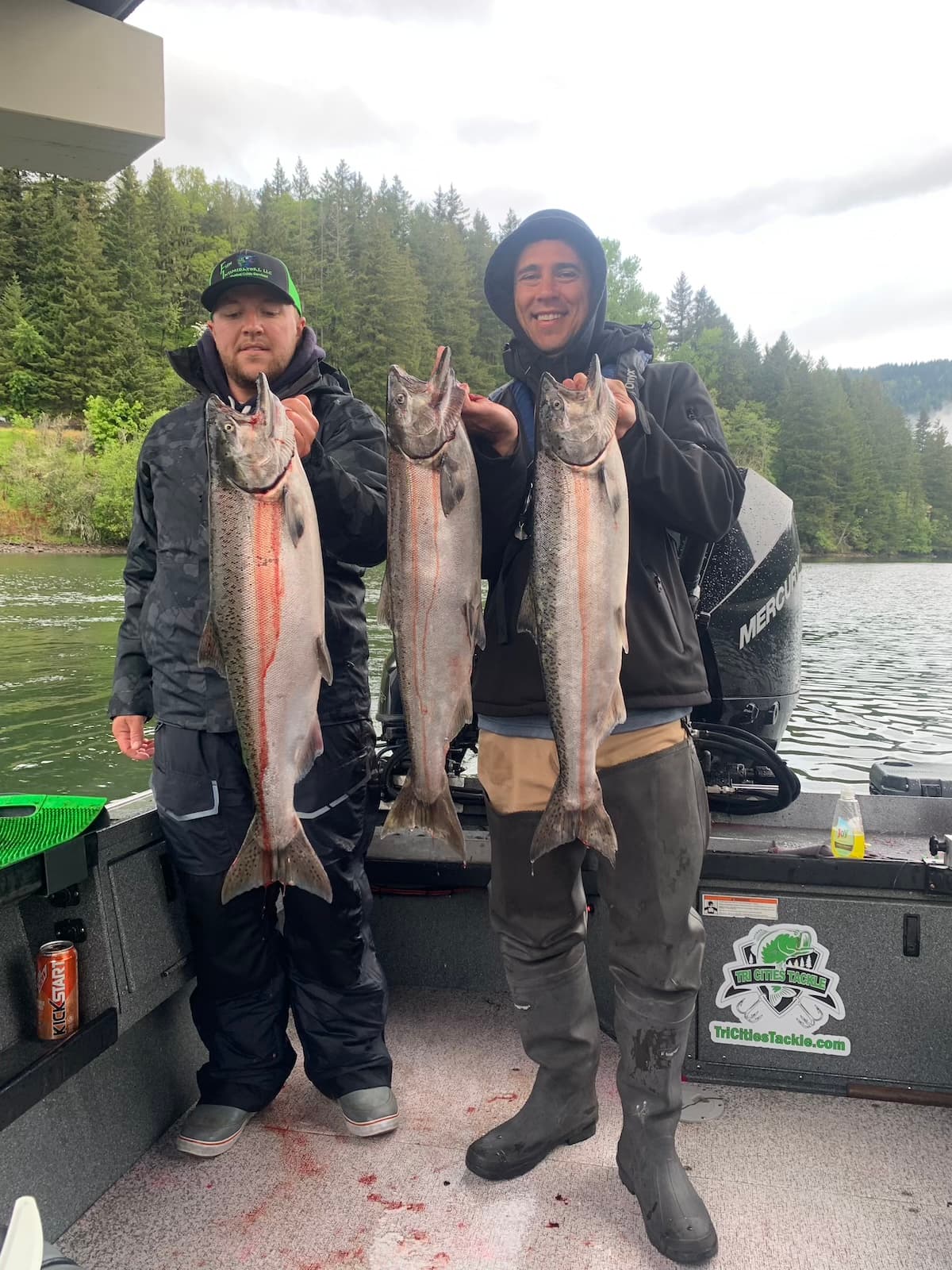 Two anglers holding three chinook salmon on guided fishing boat in Washington
